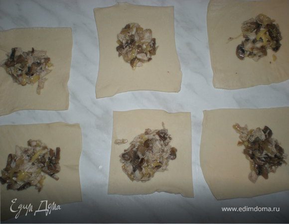 Размороженное дрожжевое слоёное тесто раскатать и разрезать на квадраты. В середину каждого положить начинку.