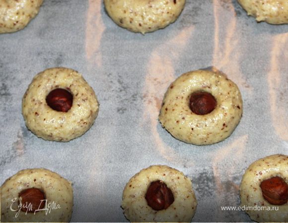 Противень застелить бумагой и выкладывать печеньки небольшими шариками.В центр вдавить орешек.