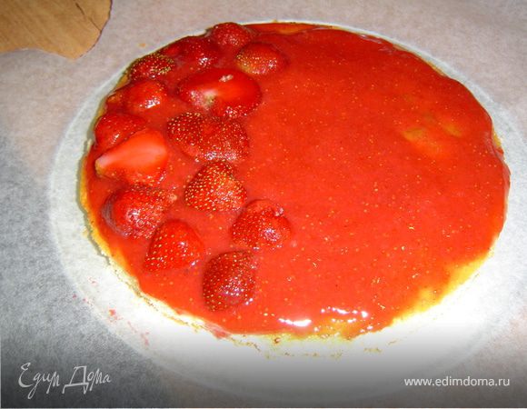 Дно разъемной формы застилаем пищевой бумагой, а в центр выкладываем корж. Перетираем клубнику с сахаром и 2/3 этого пюре наносим на корж. Сверху пюре выкладываем клубнику, разрезанную пополам.