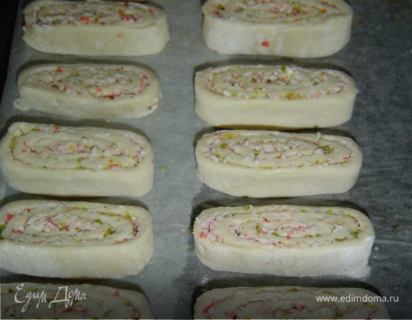 Раскладываем рулетики на противне, застеленном пищевой бумагой, и смазываем яйцом.