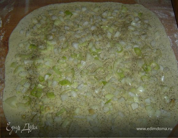 Раскатываем его,посыпаем измельченным луком и перцем,