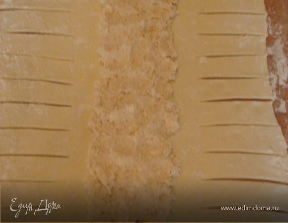 Раскатываем готовое слоеное тесто, надрезаем полосочками с обеих сторон, на середину выкладываем курятину с плавленым сыром.