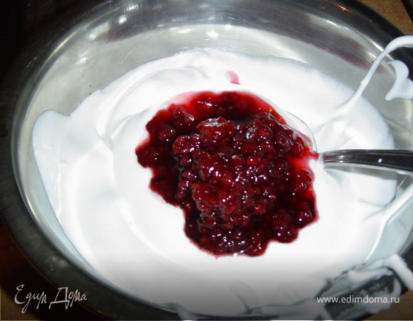 В оставшиеся белки добавьте малиновое варенье и аккуратно перемешайте, нанесите этот крем на второй корж.