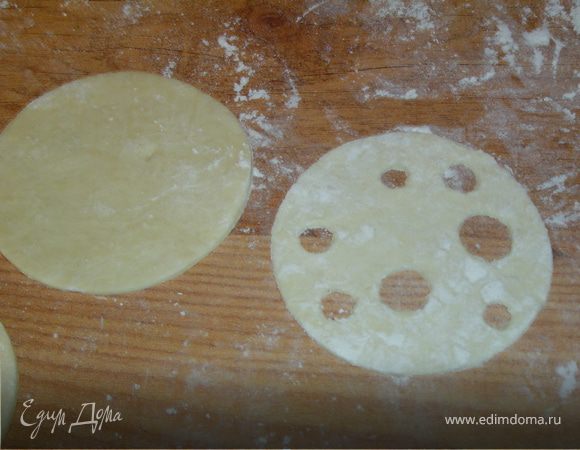 Раскатываем тесто и круглой формой вырезаем два одинаковых кружочка.В одном из них произвольно вырезаем несколько кружочков,иммитируя дырочки в сыре.Это кружочек будет являться в слоечке кусочком сыра.