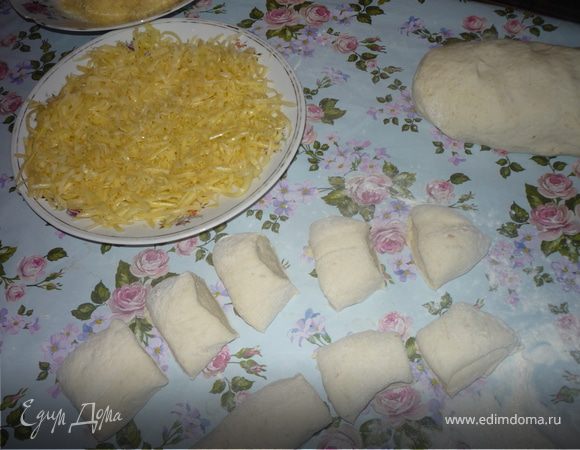 1/3 сыра трем на мелкой терке, 1/3 сыра трем на крупной терке. Тесто делим на 2 части. Из одной готовим булочки, из другой батончики (сырные палочки. Для приготовления булочек тесто выкладываем на посыпанный мукой стол, сверху присыпаем мукой и вымешиваем тесто так, что бы оно стало эластичным, отлипало от стола, держало форму. Тесто скатываем в цилиндр и нарезаем 12 кусочков.