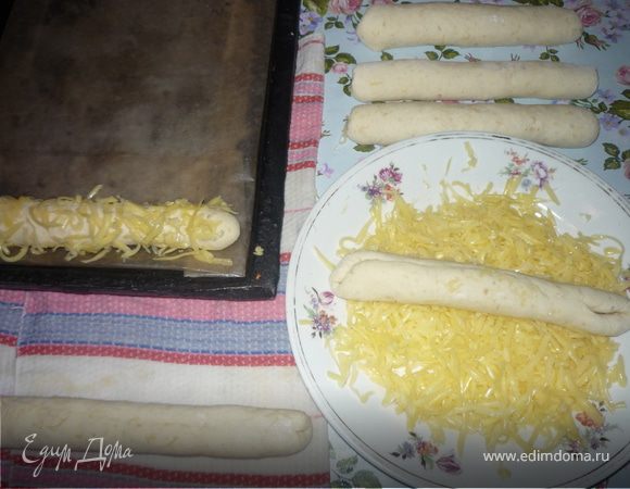 Батончики прокатываем по влажной салфетке в одном направлении (либо от себя. либо к себе), придавая форму цилиндра толщиной 2-3 см. Затем швом вверх кладем на тертый на крупной терке сыр, и выкладываем на смазанный маслом противень швом вниз (можно и на бумагу, т.к. Вам выбирать что легче: оторвать от противеня прилипший сыр или от батончиков прилипшую бумагу). Выкладываем подальше друг от друга, т.к. тесто очень сильно подходит.