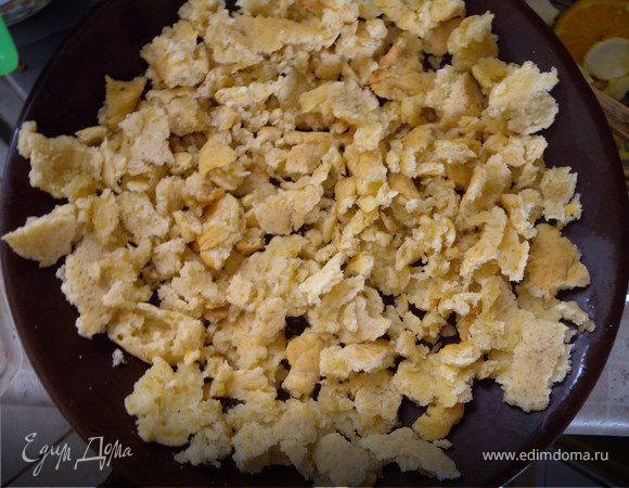 Порвать корж на кусочки, выложить на форму или тарелку для микроволновки, немного примять.