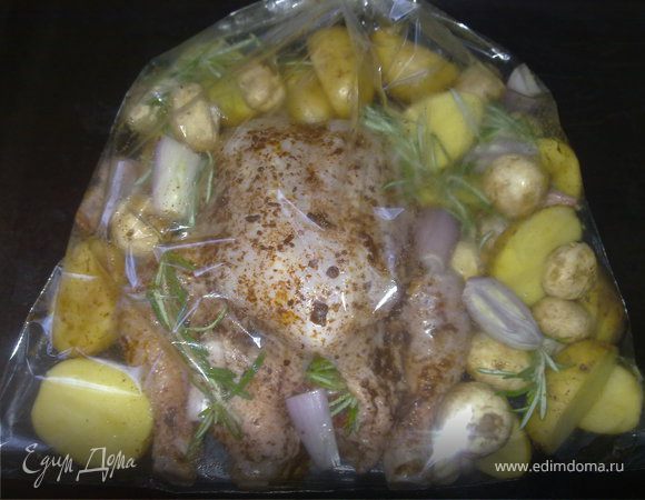 Смешать в небольшой миске паприку с оливковым маслом  в однородную массу. Курицу помыть, равномерно посолить. С помощью кулинарной кисточки смазать всю поверхность курицы массой из оливкового масла и паприки. Во внутрь курицы положить веточку розмарина. Картофель и грибы хорошо помыть. Нарезать картофель в кожуре на половинки, так же нарезать лук шалот. Шампиньоны нарезать  пополам, если они не крупные – то оставить целиком. Птицу уложить в пакет для затекания, обложить овощами и грибами и сверху на овощи положить розмарин. Рукав для затекания плотно завязать, оставив внутри воздух. Противень с рукавом поставить в предварительно разогретую до 200 градусов духовку.