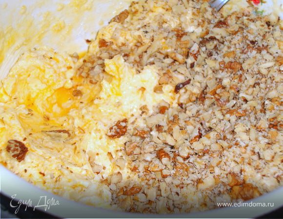 Грецкие орехи измельчить не очень мелко. Для этого их можно положить в пакет и раскатать его скалкой.
	
 
 Добавить орехи в масляно-желтковую смесь.