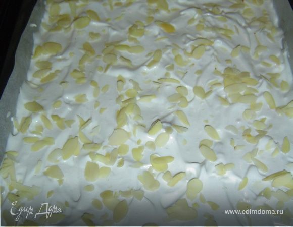 а сверху выкладываем взбитые белки. Сверху безе посыпаем половиной нормы миндальных хлопьев. 