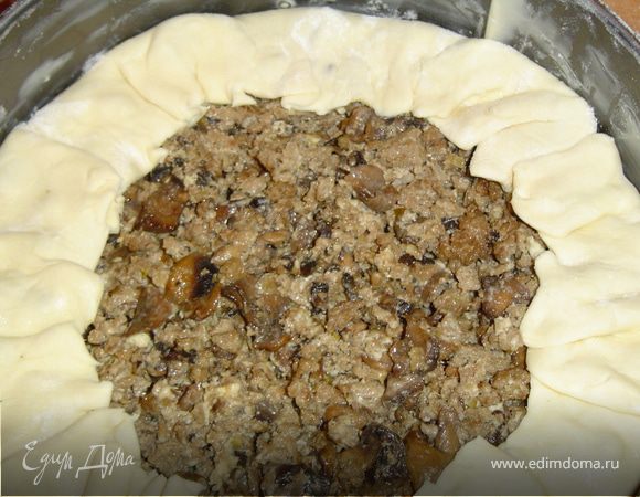 Раскатываем слоеное тесто.Форму смазываем маргарином и укладываем тесто.Выкладываем начинку и формируем бортик.