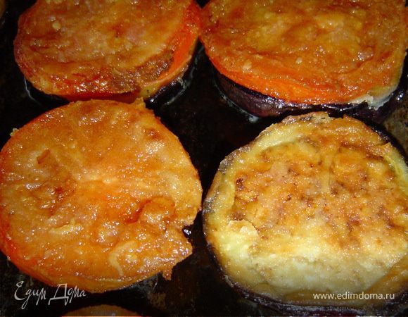 На противень смазанный растительным маслом выкладываем кружочки баклажанов, перчим и посыпаем их измельченным чесноком.