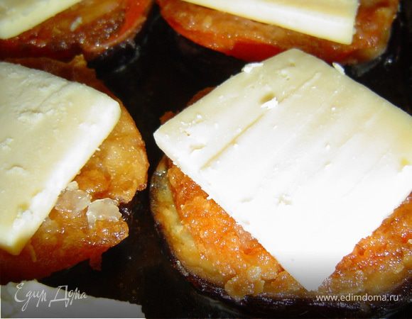 Сверху кладем кружочки помидоров, и также перчим и посыпаем чесноком и измельченной зеленью петрушки, все это накрываем кусочками сыра и запекаем в духовом шкафу при температуре 180-190гр. до золотистого цвета.