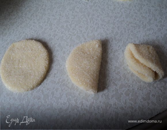 в неглубокую тарелку насыпать сахар (~1 стакан),каждый "кругляшок" обмакивать в сахар,слаживать сахаром внутрь,полукруг обмакиваем в сахар и опять складываем до получения треугольника.