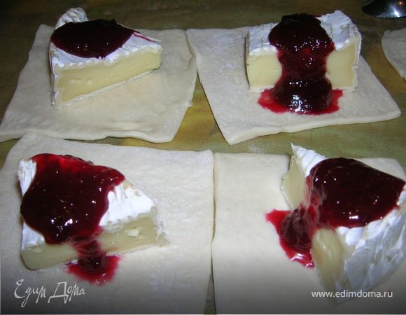 Положить на квадратики теста камамбер. Полить 1 чайной ложкой клюквенного соуса. 