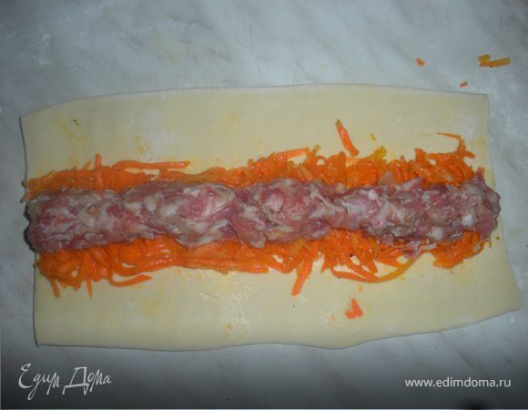 Готовое тесто раскатываем,в серединку выкладываем морковку на нее выкладываем колбаской фарш,сворачиваем рулетом и режем на маленькие рулетики.