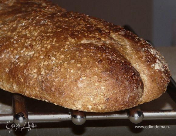 На деко положить бумагу, на нее батон, смазать водой, посыпать и немного вдавить кунжут и накрыть.
Через час можно ставить в духовку(сделать надрезы ножом) 220С на 20 минут, а снизу подставить миску с водой. После 20 минут убрать миску и убавить температуру до 200С, оставить на +-15 минут.
Вынуть, на решетке остудить.
