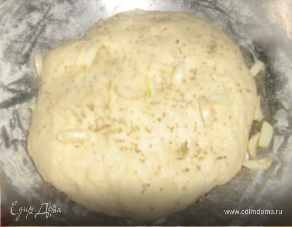 Чеснок очистить, вынуть середину. Нарезать каждый зубчик на 4 части. Добавить чеснок и орегано в тесто. Разделить тесто на 2 части. Подготовить 2 формы - смазать маслом. Фокачча в идеале продолговатая, но мне нравится  округлая неправильная форма. Тесто размять по размеру формы. Приплюснуть пальцами, оставить подходить на 10-15 минут в теплом месте. 