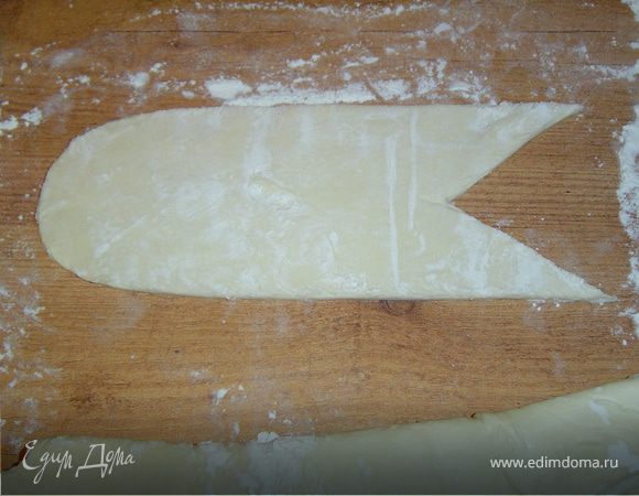 Раскатываем тесто и ножом прорезаем овал,с одной стороны вырезаем в центре треугольник.В итоге получаются два будущих ушка нашего волка.