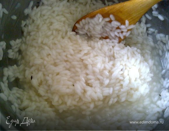 В кастрюле с толстым дном разогреть оливковое масло и обжарить в нем рис, чтобы он пропитался маслом, и влить в кастрюлю 1/3 бульона. Как только бульон закипит, уменьшить температуру и варить, постоянно помешивая и добавляя бульон по мере выкипания. Вместе с последней порцией бульона добавить мартини. Когда рис будет готов – посолить его.

