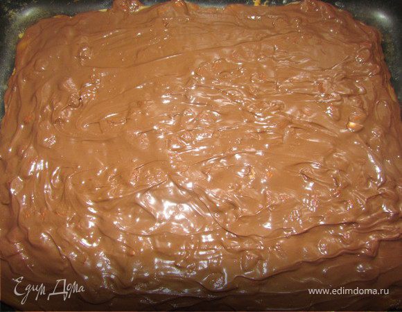 На готовый корж выкладываем горячую карамель и выравниваем лопаткой. Для глазури необходимо шоколад поломать на кусочки и растопить его на водяной бане. В шоколад добавить орехи, перемешать и выложить смесь на карамель. Шоколад надо быстро разровнять и поставить печенье в холодильник на  час. Затем нарезать его произвольно. 