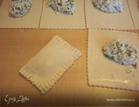 На середину каждого квадратика выложить по столовой ложке с горкой начинки. Края теста смазать белком.