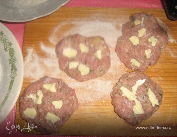 Масло должно быть замороженным. Нарезать его на очень маленькие кубики. Из фарша сформировать лепешки, разложить на них кусочки масла, затем сформировать котлеты. Масло должно пропитать котлету во время жарки, если оно не будет замороженным, то вытечет.