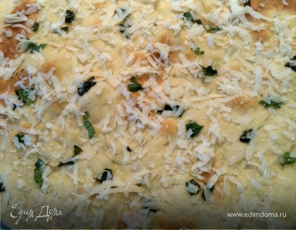 Залить дрожжи теплым кефиром, добавить пол стакана  муки грубого помола, и пол стакана обычной, и базилик. Замесить тесто, оставить на час, лучше на два в теплом месте. В оливковое масло добавить чеснок. Перемешать. Затем добавить в тесто оставшуюся муку, оливковое масло с чесноком и замесить тесто. Выложить  очень тонким слоем на противень, застеленный бумагой для выпекания (я на ней и раскатывала тесто) и промазать оливковым маслом с чесноком. Выпекать 8—10 минут при 180 градусах. Затем достать, еще раз промазать маслом, посыпать тертым пармезаном, и в духовку на 2 минуты, чтобы расплавился сыр.