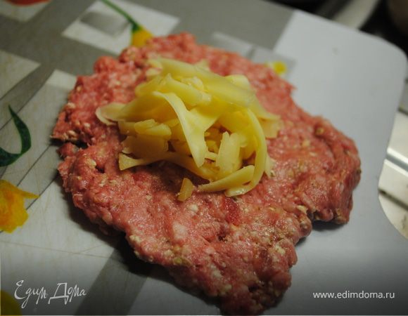 Сыр натереть на терке.
Ложкой взять небольшое количество фарша и сделать из него лепешку. Сверху выложить сыр.