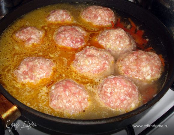 Из фарша Скатаем колобки размером немного больше куриного яйца. Выложим их к пассированным овощам и зальем кипятком. Плотно накроем крышкой и убавим нагрев до предельно слабого.
