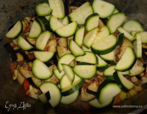 С баклажанов слить горький сок, отжать, добавить в казанок. Туда же отправить цукини. Тушить минут 15.