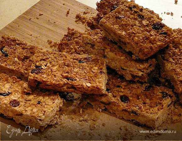 Разогреть духовку до 175С. Выложить овес, миндаль и стружку на деко и подсушить 10 минут. В кастрюльке пару минут проварить мед, масло и соль с ванилью.  Сухие ингридиенты, перемешать с медовой смесью и добавить клюкву и цедру. В огнеупорное блюдо на бумагу выложить и утромбовать. Печь 30 мин при 150С. Вынуть, остудить часа 2 и потом нарезать ножом для хлеба на полоски (они будут плотными). хранятся в холодильнике в бумаге