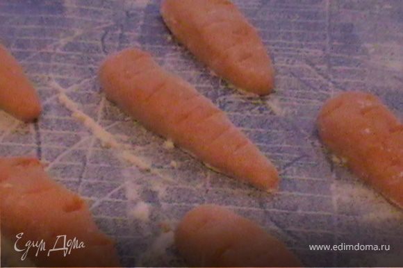 На рабочей поверхности из теста формируем морковки.