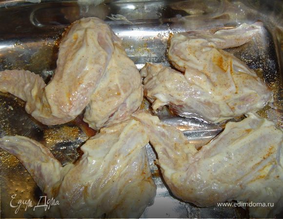 Берем куриные крылышки, смазываем сметаной и посыпаем специями.