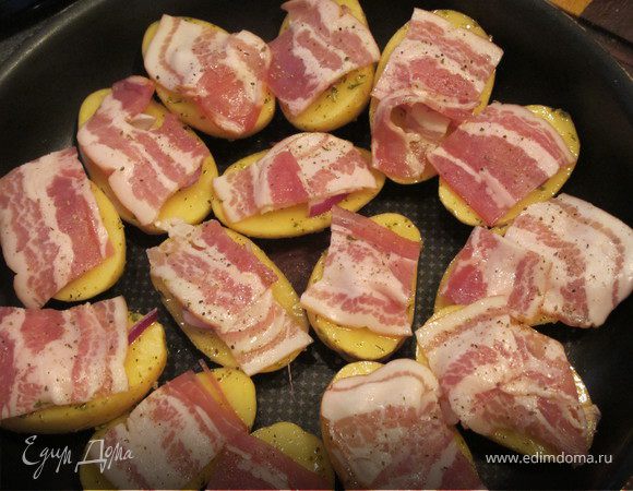 Картошку выложить на противень кожей вниз.сверху положить перышки лука и бекон, присыпать орегано и отправить в разогретую духовку (200 гр.) на 30-40 минут.