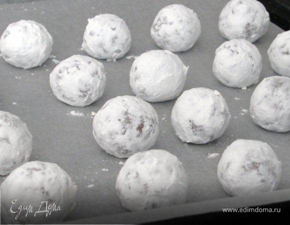 Из холодного теста сформировать шарики 2,5см в диаметре, каждый обвалять в сахарной пудре и выложить на пергамент. Лучше доставать тесто из холодильника небольшими порциями, иначе сахарная пудра на недостаточно холодном  тесте растворится и впитается и контрастные трещинки не получатся. Ну и, конечно, быстро скатывать шарики.   