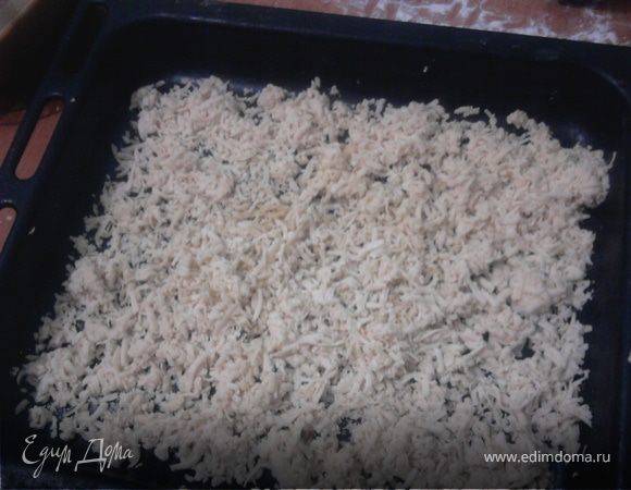 Противень смазать маслом.
Достать 1 часть теста их морозилки и натереть на крупную тёрку. Выложить на противень тонким слоем.
