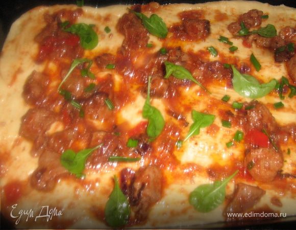Тесто выкладываем на противень. Сначала берем соус и смазываем всю поверхность, затем выкладываем мясо. Посыпаем  листиками руколлы и рубленым зеленым луком. Ставим в духовку.