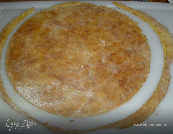 Готовый круг из теста аккуратно переносим на противень, застеленный пекарской бумагой, и выпекаем в духовке при температуре 200 гр. 7-8 минут. Готовые коржи горячими обрезаем, используя дно разъемной формы и даем остыть.