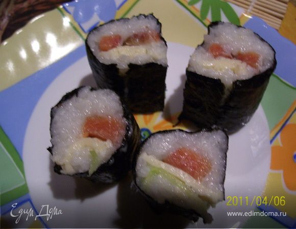 С помощью бамбуковой циновки сформировать плотный рулет. рис по всей длине рулета должен получиться плотный и ровный. Разрезать рулет пополам.