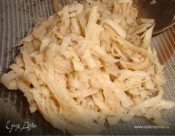 Очистите картофельные клубни, натрите на терке или мелко нарежьте, добавьте так же мелко нарезанный лук, соль, перец и хорошо перемешайте. Переложите в дуршлаг или сито, чтобы убрать лишнюю влагу.