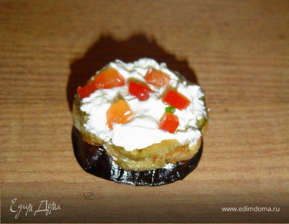 На баклажаны укладываем кружки кабачков, смазываем его творожным сыром и засыпаем зеленью и сладким перцем.