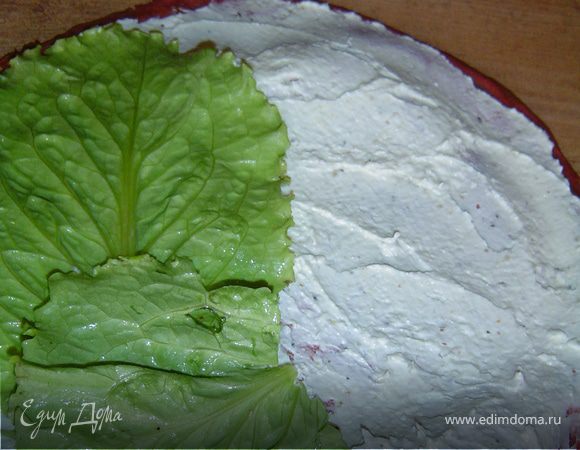 На один край кладем листья салата, их смазываем намазкой, 