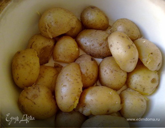 Картошку отварить в кожуре до полуготовности , дать ей остыть, разрезать вдоль пополам. В основании тажина налить 2 ст л оливкового масла и выложить картошку срезом вниз.