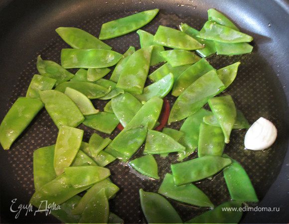 Сковороду разогреть, добавить зубчик чеснока, обжарить 2 минуты,вытащить, добавить горошек и тоненько нарезанный лук