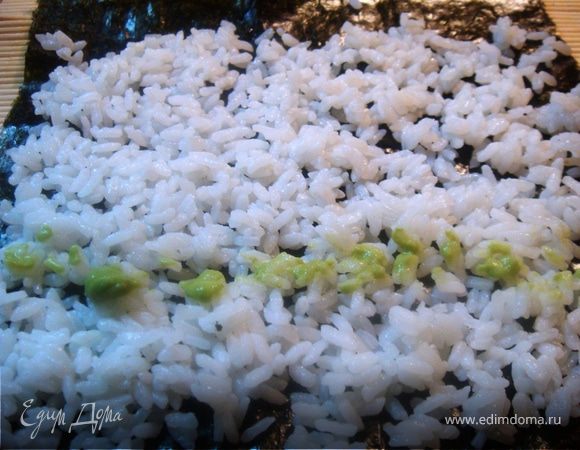 смачиваем руки в холодной воде, и жменьку остывшего рыса выкладываем на лист нори, распределяем и смазываем васаби (учитывая, что это острый соус).