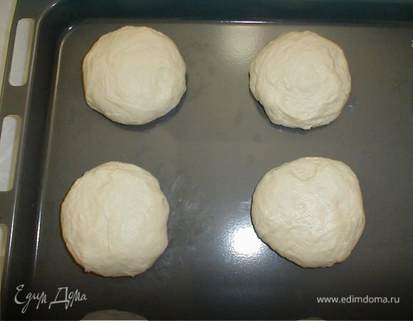 После того, как тесто подошло можно приступать к работе с тестом. Необходимо скатать шарики размером чуть меньше теннисного мяча. Должно получиться 12-15 штук. Дать тесту опять немного подойти. Из каждого шарика сформировать маленькую лепешку и середину надо украсить при помощи чекича (специальный инструмент), если под рукой нет чекича, можно заменить его вилкой. Смазать желтком поверхность кулчашек и в середину насыпать несколько семечек седаны.