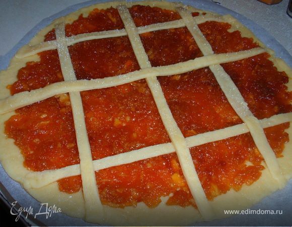 Отрезаем 1/4 часть теста (это наш переплет) и отправляем назад в холодильник. 3/4 теста раскатываем, выкладываем конфитюр. Из оставшегося теста делаем тоненький переплет. В каждый квадратик, на яблочную начинку, выкладываем сливочное масло. Присыпаем щепоткой сахара.