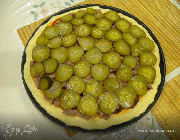 Следующий слой — соленый огурец, нарезанный тоненькими кружочками.