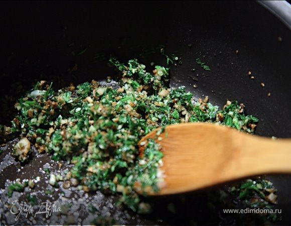 У петрушки удалить стебли,листочки порубить вместе с чесноком как можно мельче.Ножки шампиньонов тоже очень мелко порубить и обжарить на хорошо разогретом масле до золотисто-коричневого цвета.Добавить петрушку с чесноком,перемешать и сразу снять с огня.